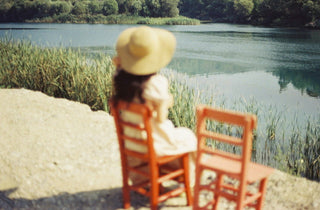 Woman in summer hat sitting in a chair by the water
